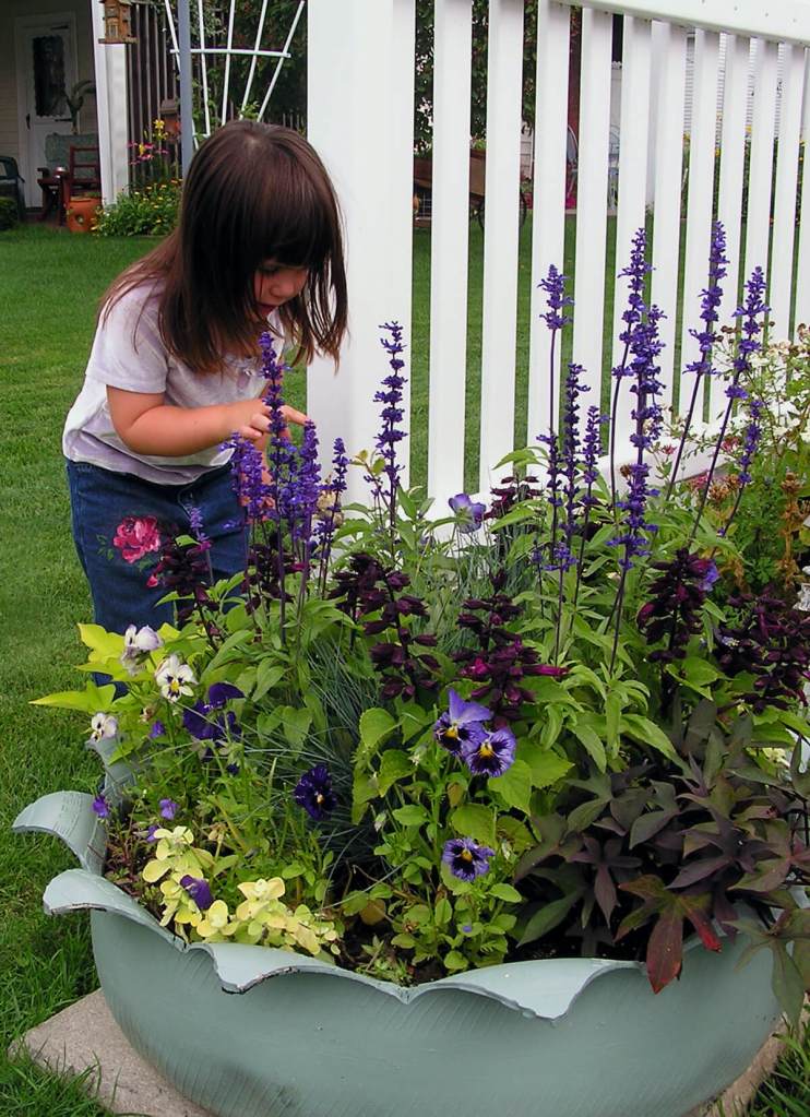 Recycled tire planter, with child admiring flowers